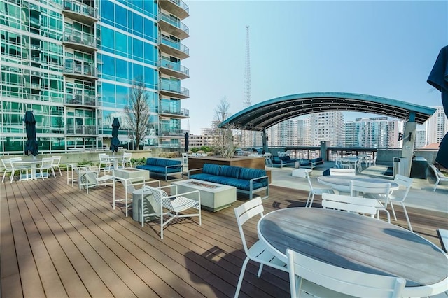 wooden terrace featuring a view of city and an outdoor living space with a fire pit