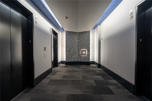 corridor with elevator, baseboards, and carpet floors