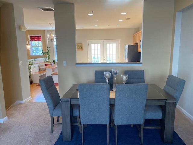 dining room featuring light colored carpet and an inviting chandelier