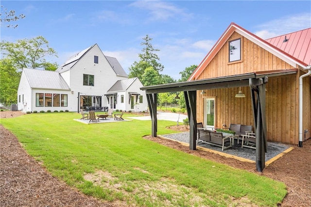 rear view of property with outdoor lounge area, a standing seam roof, a patio, a yard, and metal roof