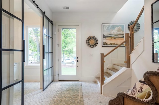 entryway featuring stairs, a barn door, visible vents, and plenty of natural light