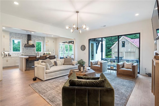 living room featuring light wood-style floors, visible vents, recessed lighting, and a chandelier