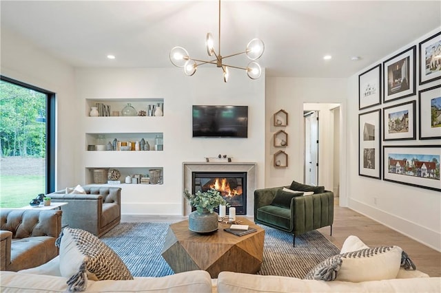 living area featuring built in features, a fireplace, wood finished floors, a notable chandelier, and recessed lighting
