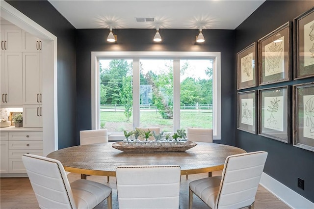 dining area featuring visible vents, baseboards, and light wood finished floors
