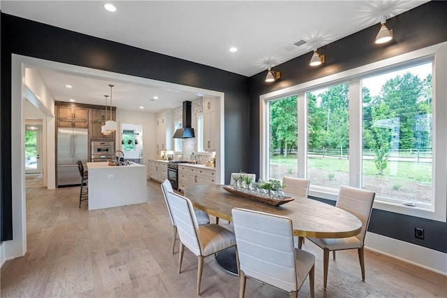 dining room featuring baseboards, light wood-style flooring, and a wealth of natural light