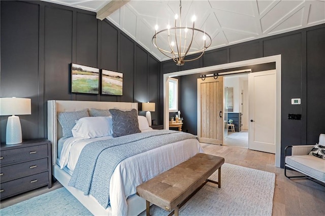 bedroom featuring a decorative wall, light wood-type flooring, a barn door, and a notable chandelier