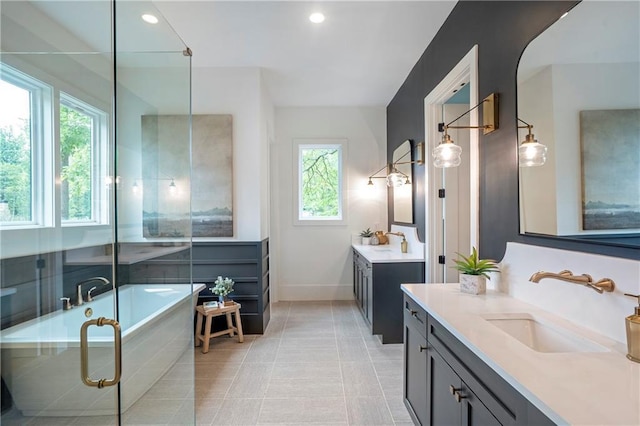 full bath with baseboards, a sink, two vanities, and a healthy amount of sunlight