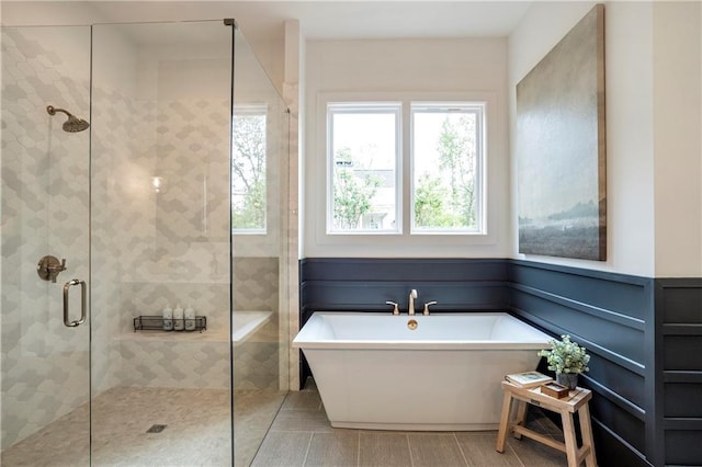 bathroom featuring wainscoting, a soaking tub, and a shower stall