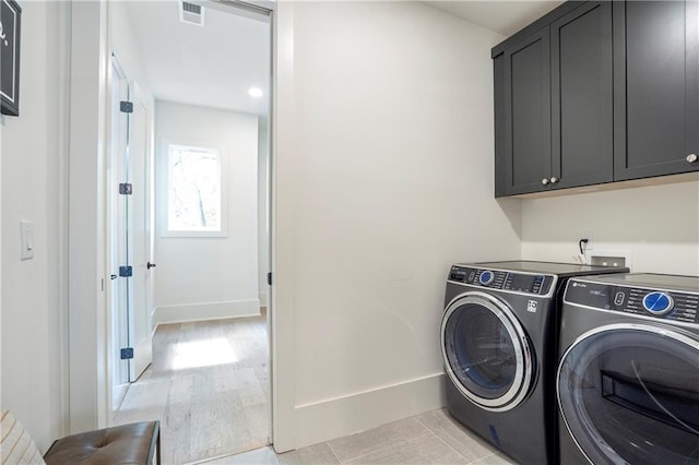 laundry area featuring visible vents, cabinet space, baseboards, and washing machine and clothes dryer