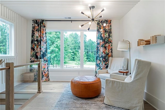 sitting room with baseboards, a chandelier, wood finished floors, and visible vents