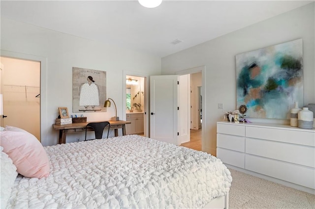 bedroom featuring connected bathroom, visible vents, and a walk in closet