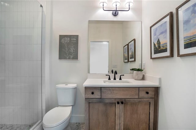 bathroom with vanity, baseboards, toilet, and tiled shower