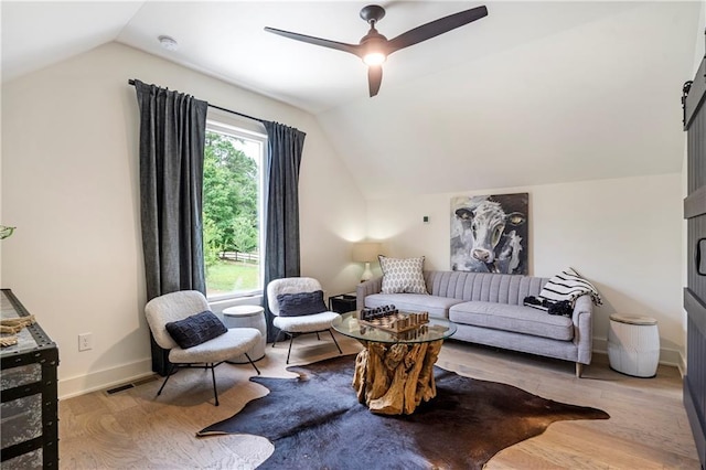 living area with wood finished floors, baseboards, ceiling fan, and lofted ceiling