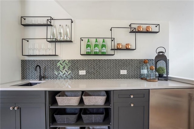 kitchen featuring gray cabinetry, open shelves, backsplash, and a sink