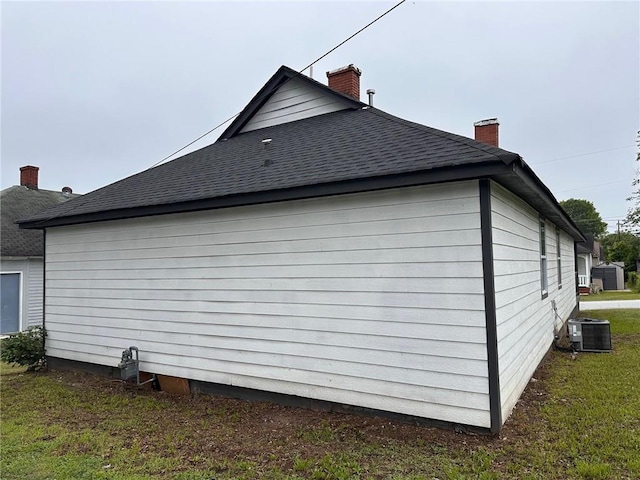 8 Hazel St, Porterdale, GA 30014 - view of property exterior featuring a chimney, roof with shingles, central AC, and a yard