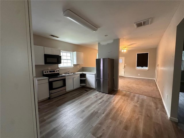 8 Hazel St, Porterdale, GA 30014 - kitchen with appliances with stainless steel finishes, a sink, white cabinets, light wood-type flooring, and light countertops