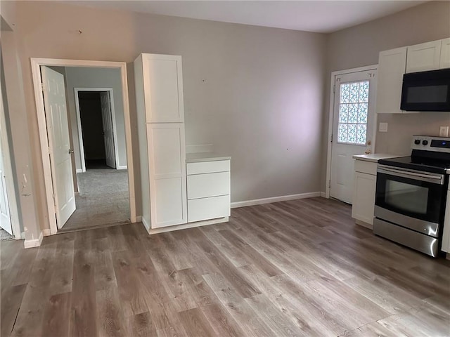 8 Hazel St, Porterdale, GA 30014 - kitchen featuring electric range, black microwave, white cabinetry, light wood-type flooring, and light countertops
