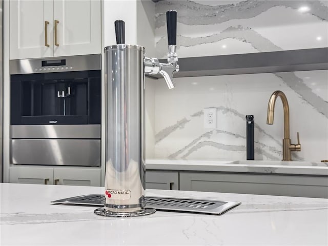 interior details featuring sink, light stone countertops, and white cabinetry