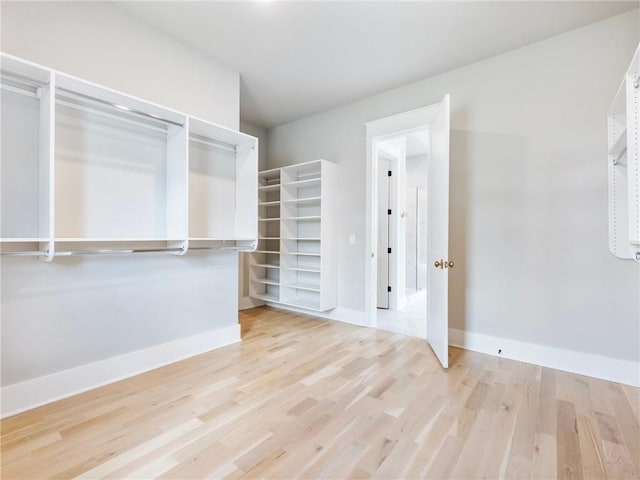 walk in closet with light hardwood / wood-style floors