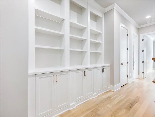 hall with light hardwood / wood-style floors and crown molding