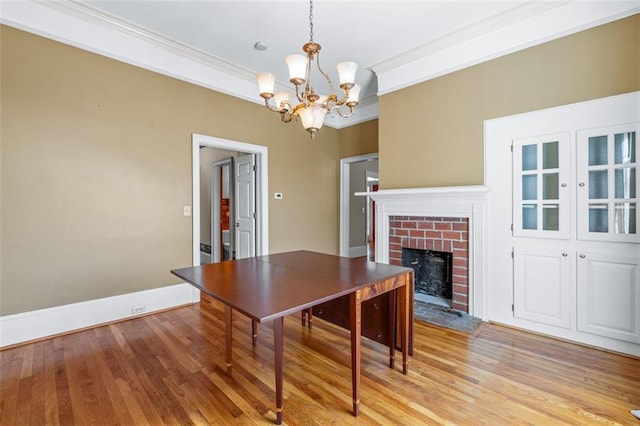 office area featuring crown molding, light hardwood / wood-style floors, a fireplace, and a chandelier