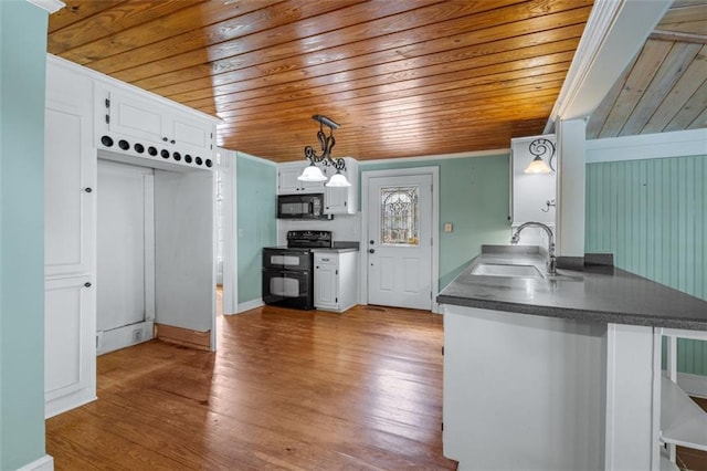 kitchen featuring hardwood / wood-style flooring, black appliances, white cabinetry, and decorative light fixtures