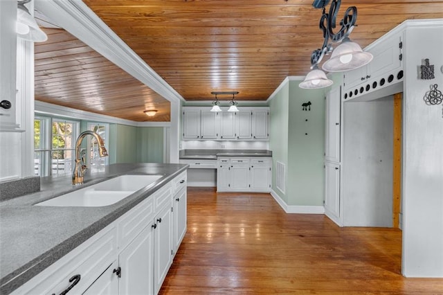 kitchen featuring sink, ornamental molding, white cabinetry, hardwood / wood-style flooring, and wooden ceiling