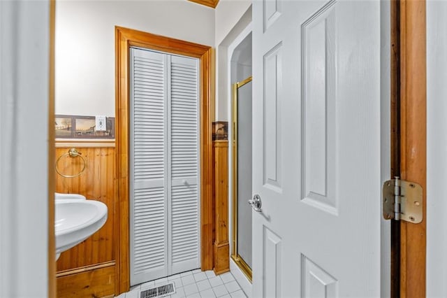 bathroom with a shower with door, tile patterned floors, and sink