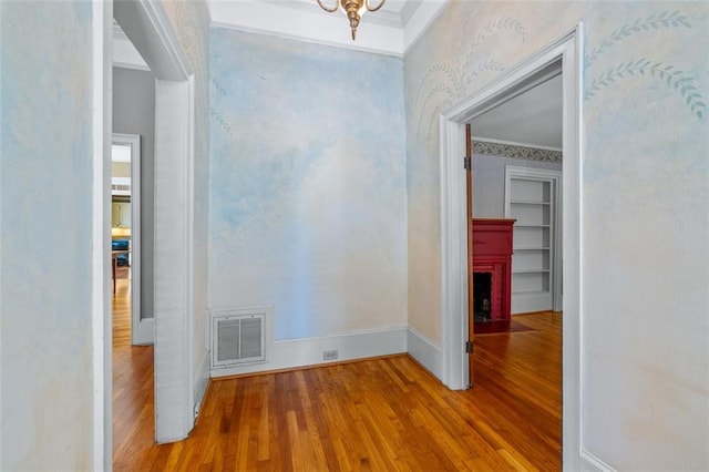 corridor featuring light hardwood / wood-style flooring, crown molding, and built in features