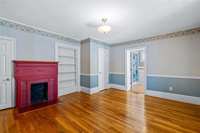 unfurnished living room with built in shelves and hardwood / wood-style flooring