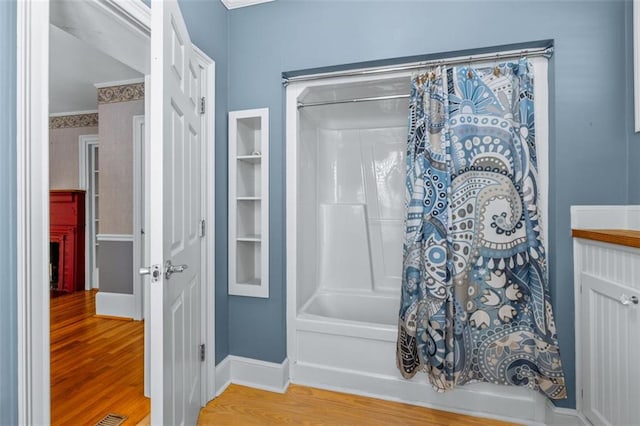 bathroom featuring shower / bath combo, crown molding, and hardwood / wood-style floors