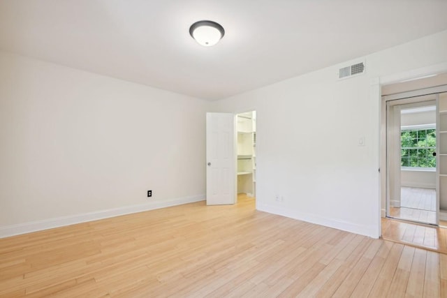 empty room featuring light wood-type flooring, visible vents, and baseboards