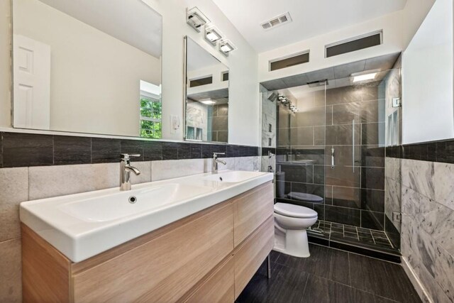 bathroom with vanity, tile walls, toilet, and an enclosed shower