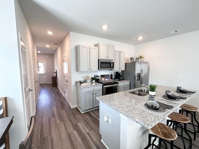 kitchen with recessed lighting, dark wood-style flooring, a sink, a kitchen breakfast bar, and appliances with stainless steel finishes