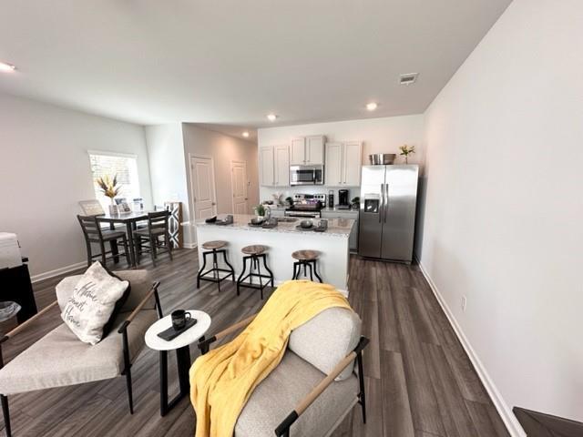 kitchen featuring stainless steel appliances, a center island, baseboards, and dark wood-style floors