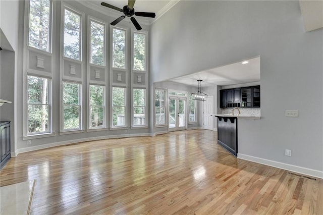 1723 Woodbow Path, Dacula, GA 30019 - unfurnished living room with ceiling fan, ornamental molding, a high ceiling, light wood-style floors, and a chandelier