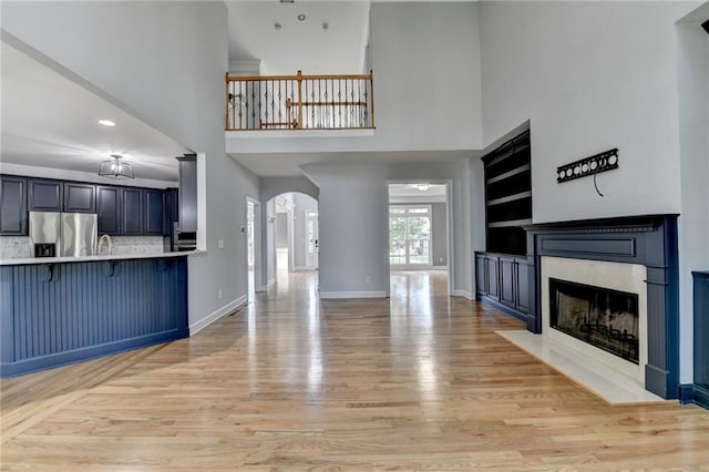 1723 Woodbow Path, Dacula, GA 30019 - unfurnished living room with a high ceiling, arched walkways, light wood-style flooring, a premium fireplace, and recessed lighting