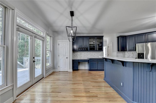 1723 Woodbow Path, Dacula, GA 30019 - kitchen featuring stainless steel fridge with ice dispenser, a breakfast bar area, light countertops, decorative backsplash, and light wood-style floors