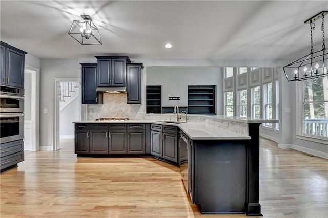 1723 Woodbow Path, Dacula, GA 30019 - kitchen with a peninsula, appliances with stainless steel finishes, backsplash, light wood-type flooring, and under cabinet range hood