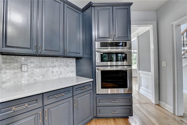 1723 Woodbow Path, Dacula, GA 30019 - kitchen featuring stainless steel double oven, light wood-style flooring, tasteful backsplash, light countertops, and gray cabinetry