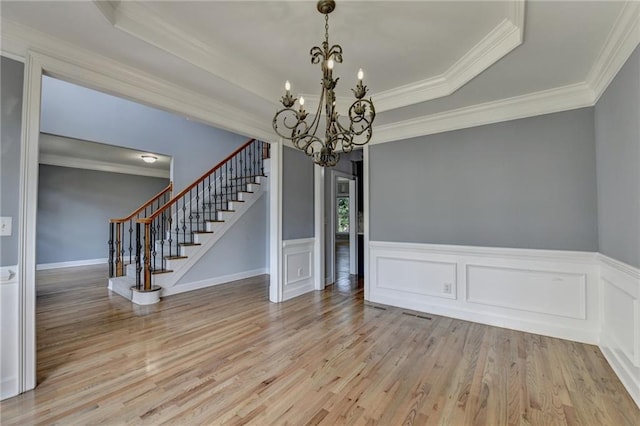 1723 Woodbow Path, Dacula, GA 30019 - unfurnished dining area with a chandelier, stairs, light wood-style flooring, crown molding, and a raised ceiling