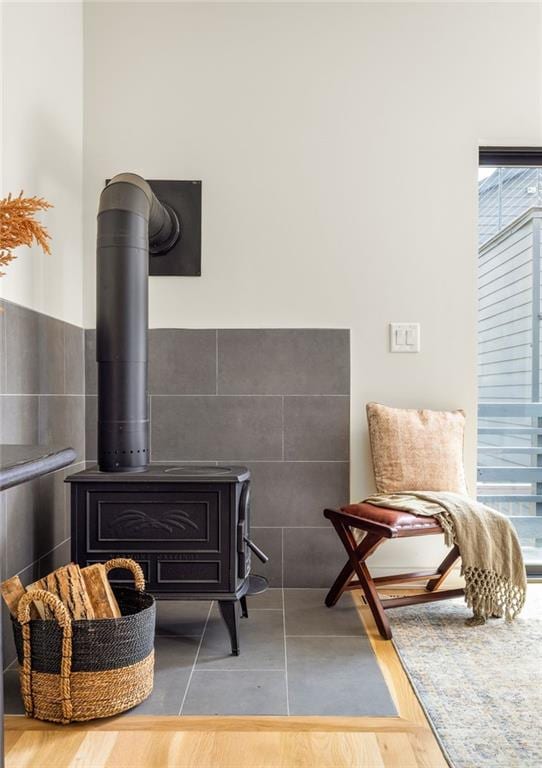 living area featuring hardwood / wood-style floors, a wood stove, and tile walls