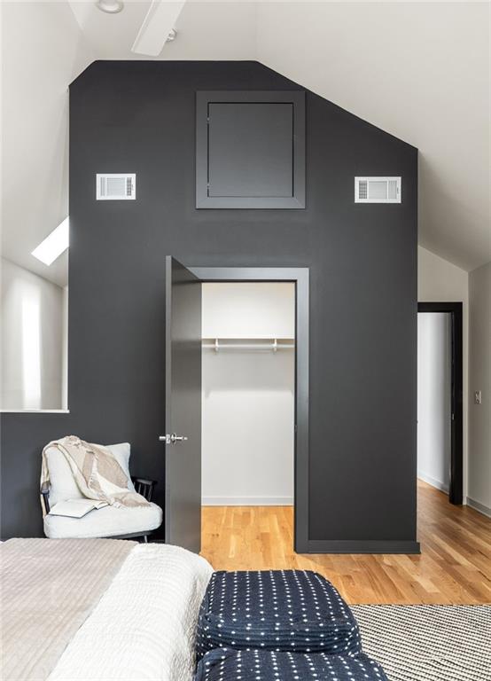 bedroom featuring a walk in closet, lofted ceiling, light hardwood / wood-style floors, and a closet