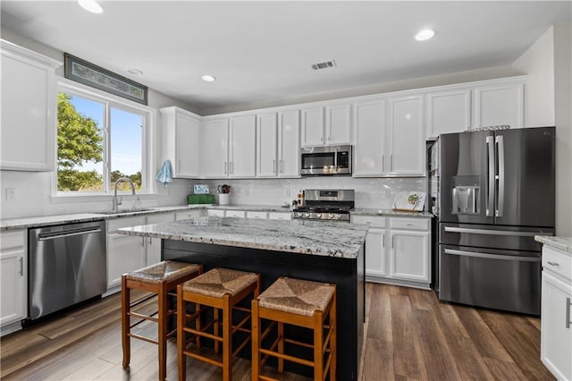 kitchen featuring appliances with stainless steel finishes, a sink, white cabinetry, backsplash, and recessed lighting