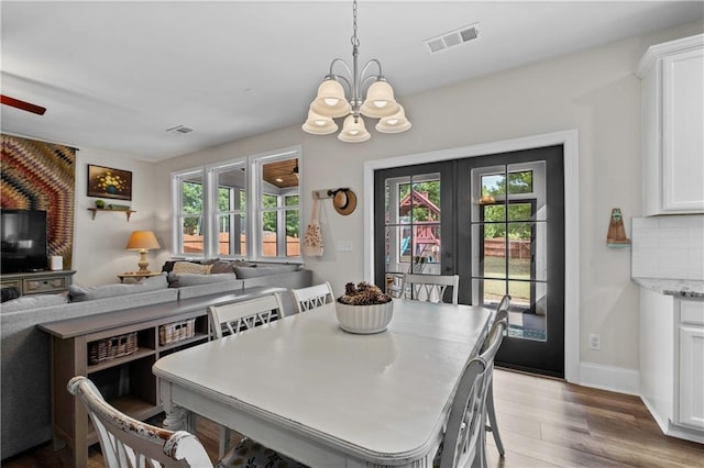 dining space featuring a chandelier, healthy amount of natural light, wood finished floors, and french doors