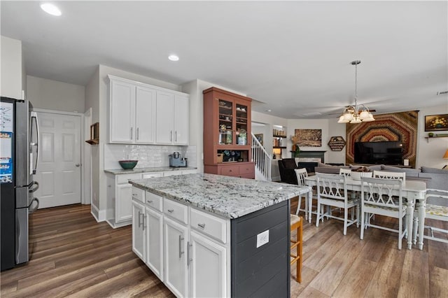 kitchen featuring freestanding refrigerator, open floor plan, white cabinets, wood finished floors, and recessed lighting