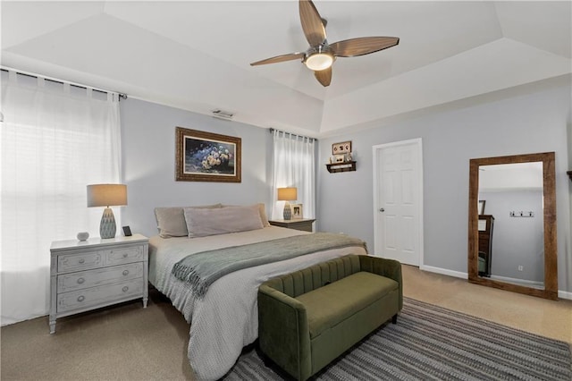 carpeted bedroom featuring ceiling fan, a raised ceiling, and baseboards