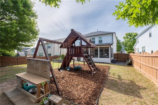 rear view of house featuring a playground and a sunroom