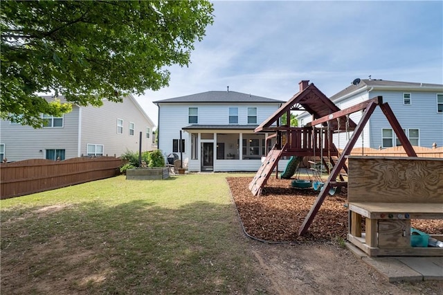 rear view of property featuring a playground and a sunroom