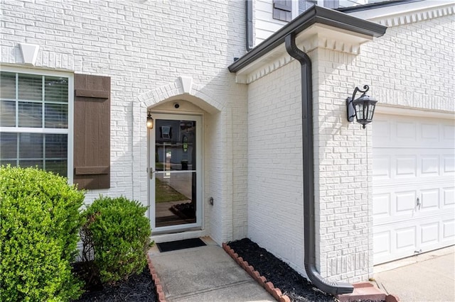 entrance to property featuring an attached garage and brick siding